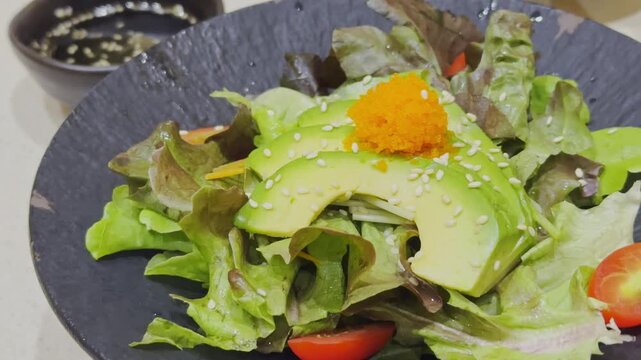 Close-up video of a fresh Japanese-style avocado salad beautifully arranged with mixed vegetables and traditional Japanese dressing. Healthy and colorful salad presentation showcasing authentic Japane