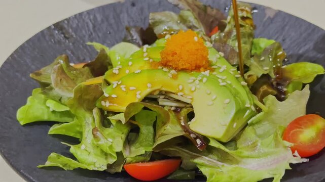 Close-up video of a fresh Japanese-style avocado salad beautifully arranged with mixed vegetables and traditional Japanese dressing. Healthy and colorful salad presentation showcasing authentic Japane