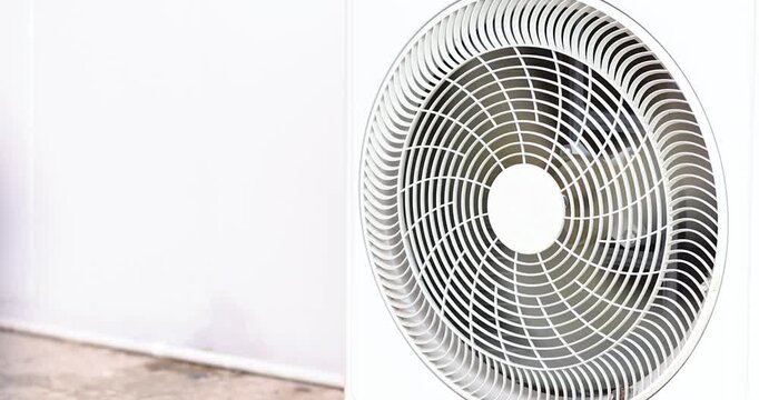 Outdoor air conditioner condenser unit with cooling fan operating. Ideal for HVAC, cooling system, energy efficiency, maintenance, residential and commercial technology, close-up