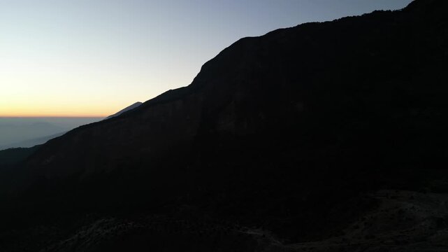 Drone footage capturing a sunrise moment at Mount Papandayan, West Java, Indonesia. Clear cloudless sky with a blue-to-orange gradient stretching across the horizon.
