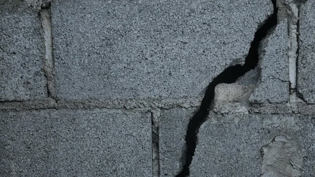 Weathered Grey Concrete Block Wall Large Diagonal Crack Close Up Urban Decay Structural Damage Grunge Texture Background Portrait