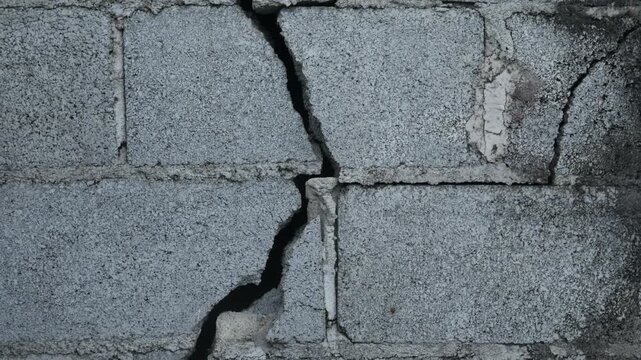 Weathered Grey Concrete Block Wall Large Diagonal Crack Close Up Urban Decay Structural Damage Grunge Texture Background Portrait