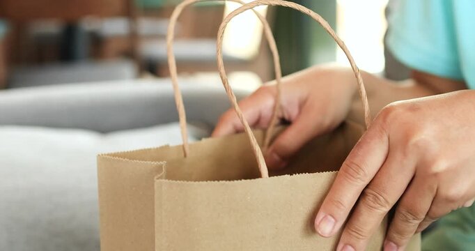 Woman hands opening and checking inside a paper shopping bag, shopping, retail, delivery, unboxing, packaging, eco-friendly products, and consumer lifestyle, close-up