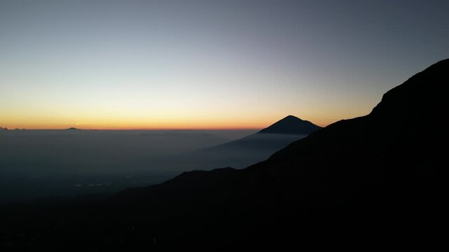 Drone footage capturing a sunrise moment at Mount Papandayan, West Java, Indonesia. Clear cloudless sky with a blue-to-orange gradient stretching across the horizon.