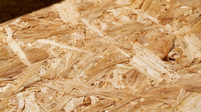 Orangish brown particle board material show detail pattern with textured background at an angle with a dark shadow space