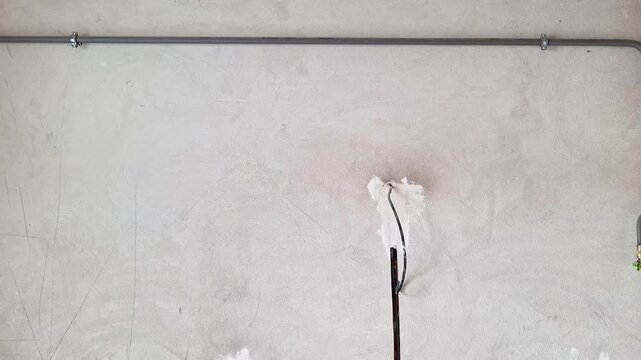 Electrical wiring installation inside a plastered wall with conduit channels, junction boxes, and power outlet points prepared for finishing during residential construction or renovation