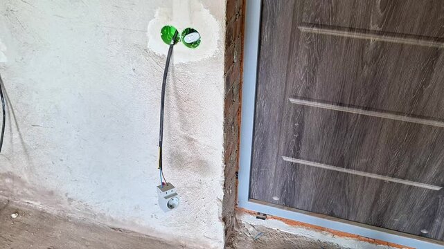 Double electrical outlet boxes installed in a freshly plastered interior wall during home renovation. Unfinished electrical installation prepared for wiring, final finishing, and interior painting