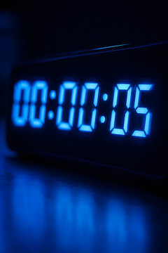 Digital alarm clock displaying time zero zero zero zero zero five with blue light glow.