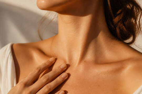 A close-up of a person's neck and shoulder, with one hand gently touching the collarbone area.