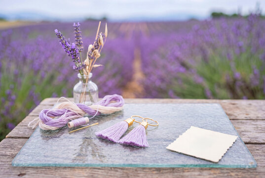 Handmade Lavender Tassel Earrings with Craft Supplies on Rustic Table in Blooming Lavender Field