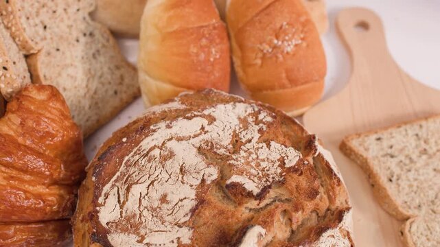 Person Picking Up Sliced Multigrain Bread From Assorted Bakery Display