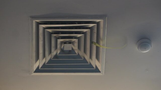 Footage of Square ceiling AC diffuser vent on a white wall, low angle close up view of commercial central air conditioning ventilation system, interior building maintenance and hvac concept.
