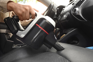 Person using handheld vacuum cleaner to clean car seat © Pixel-Shot
