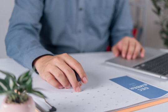 person planning schedule monthly calendar page office desk laptop pen business project tracking timeline deadline appointment reminder corporate organization workflow time management