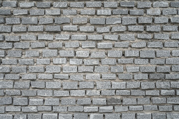 Fototapeta premium Natural dark grey stone brickwork facade and rugged masonry surface pattern for architectural design background or texture. Close-up.
