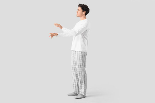 Young male sleepwalker on grey background