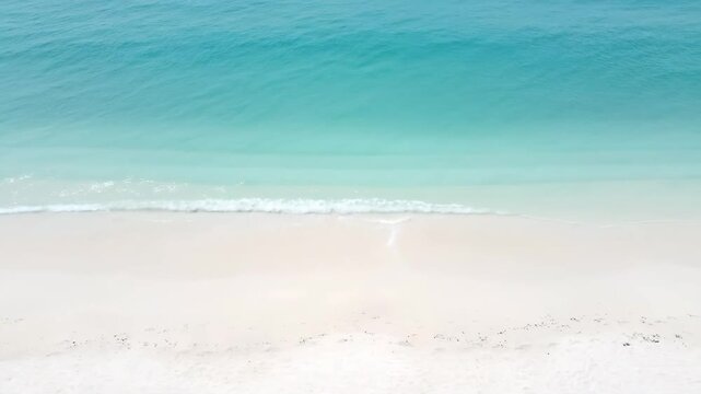 Static aerial view of minimalist white sand beach and calm turquoise sea in soft overcast daylight