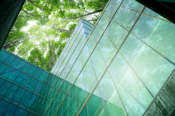 Eco-friendly building in modern city. Sustainable glass office building with trees for reducing CO2. Green architecture. Building with green environment. Sustainability corporate. Net zero emissions. © Fahroni