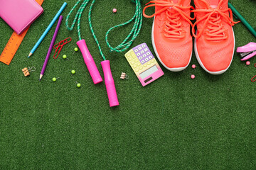 Obraz premium Sneakers, jumping rope and different stationery on artificial grass as background