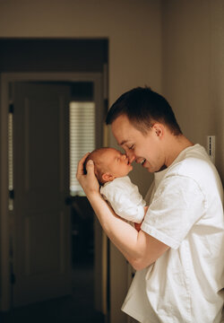 A father holds his baby in his arms with a smile.
