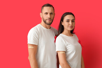 Obraz premium Young couple with red ribbons on color background. AID awareness concept