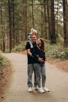 A warm family walk along a forest path. Parents are spending time with their child amidst tall trees and nature.