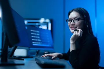 Customer service, asian female IT support engineer wearing headset working on computer code, technical helpdesk, call center, software development, cybersecurity and global corporate communications © Art_Photo