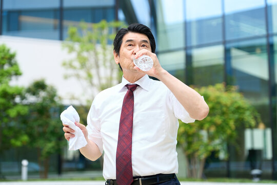 暑い屋外で水を飲むビジネスマン