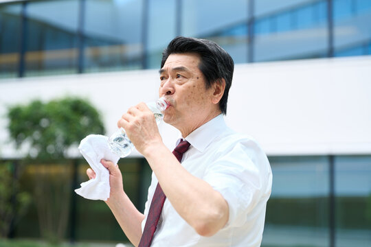 暑い屋外で水を飲むビジネスマン