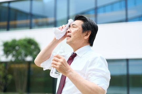 暑い屋外で汗を拭くビジネスマン