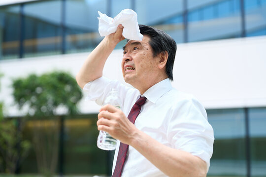 暑い屋外で汗を拭くビジネスマン