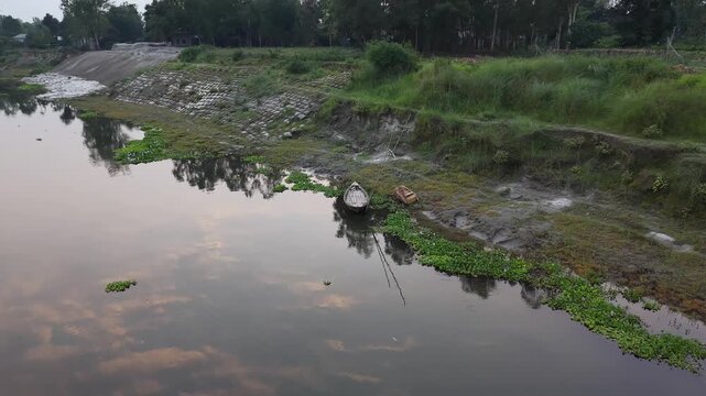 Serene riverbank with traditional boats and lush greenery reflecting dusk sky serene riverbank