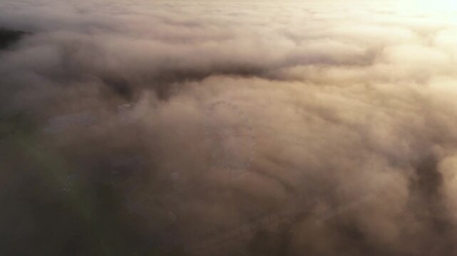 Thick rolling fog illuminated by sunset light, nature atmosphere, elevated view.