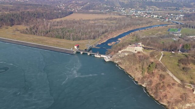 In Dobczyce, Poland, the frozen Lake Dobczyce and its dam appear beside surrounding forests and countryside near the Raba River in an aerial winter view.