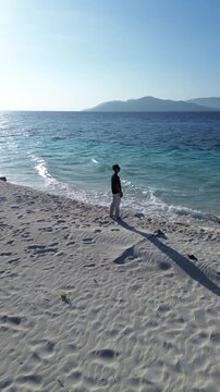 Man Standing on a Sandy Beach Looking at the Ocean