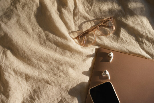 Cozy Tech Essentials on Beige Fabric with Glasses, Laptop and Phone