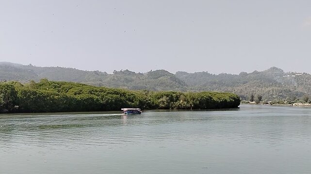 A scenic boat navigating the estuary where the river meets the sea, showcasing peaceful coastal waters, natural landscapes, and traditional maritime transportation. Perfect for illustrating fishing co