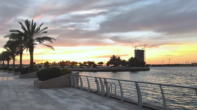 Sunset Over Al Raha Beach, Abu Dhabi with Palm Trees and Waterfront Promenade