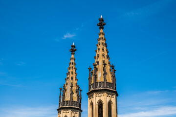 Fototapeta premium Low angle view of two ancient gothic spires and castle towers rising into a clear blue sky with copy space