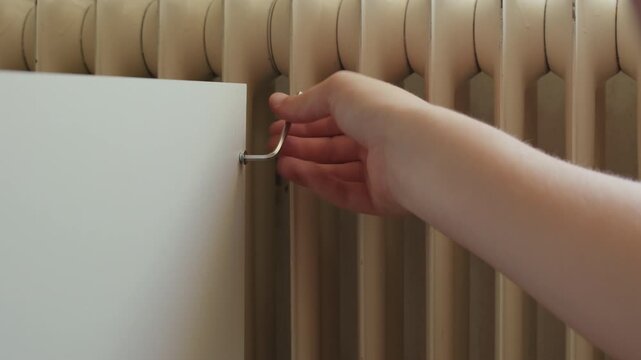 Man assembling a new wardrobe in a living room using a hand tool to install furniture hardware.