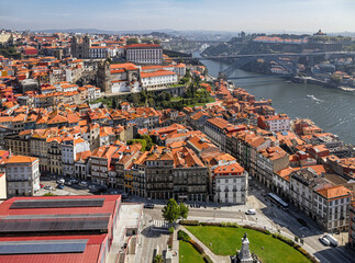 Obraz premium Elevated view over Porto old town, red rooftops, historic churches, Douro river, and iconic iron bridges in Portugal.