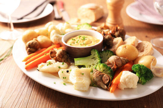 Traditional french aioli platter with cod fish sea snails and steamed vegetables