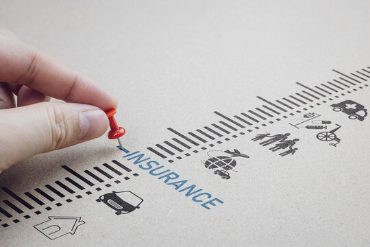 Hand placing a red pin on insurance text with life, car, home, and health icons. Concept of risk management, financial security planning, and policy protection.