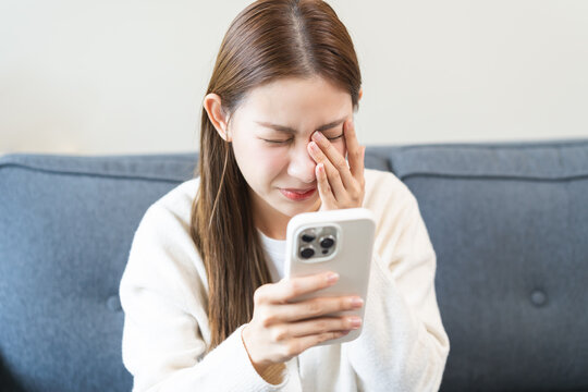 Presbyopia, Hyperopia middle aged asian woman hand rubbing her eye with vision blurred ,girl trying to read text message from smart mobile phone screen, eye disease of old, eyesight farsightedness.