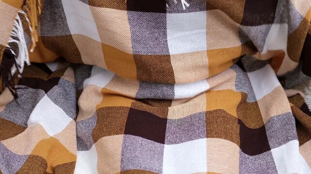 Close up of hands holding plaid wool blanket with fring