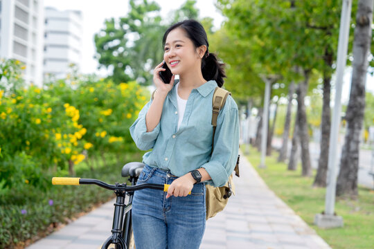 Asian girls happily walk and cycle with their cell phones in parks and on city streets.