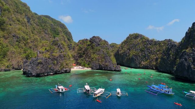 Drone view of boats and kayaks in a turquoise El Nido lagoon