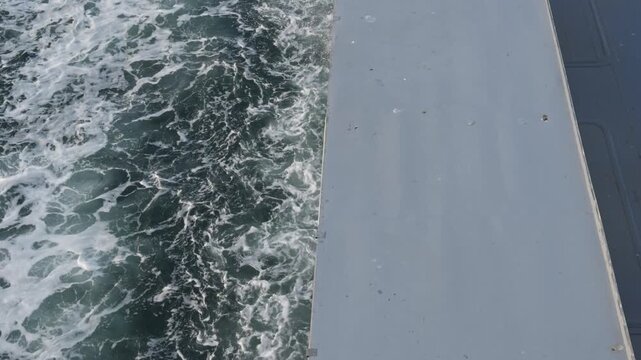 Close-up shot of white foam and churning water against a steel ship hull, dynamic wave texture and splash detail, ocean power, maritime scene.