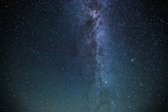 Under a dark sky, countless stars twinkle brightly, creating a stunning view of the Milky Way. Long exposure shot.