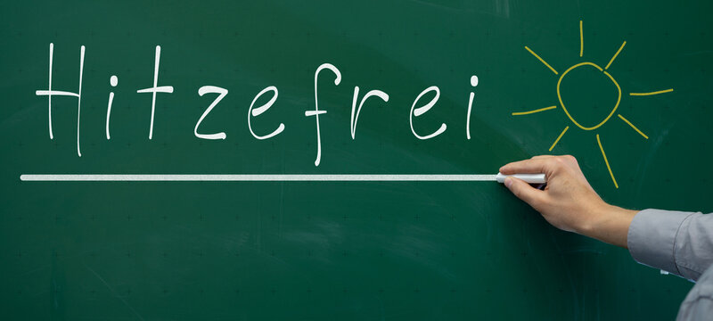 Hitzewelle - Hitzefrei an deutscher Schule - Lehrer schreibt deutschen Text mit Kreide an gr&uuml;ne Schultafel